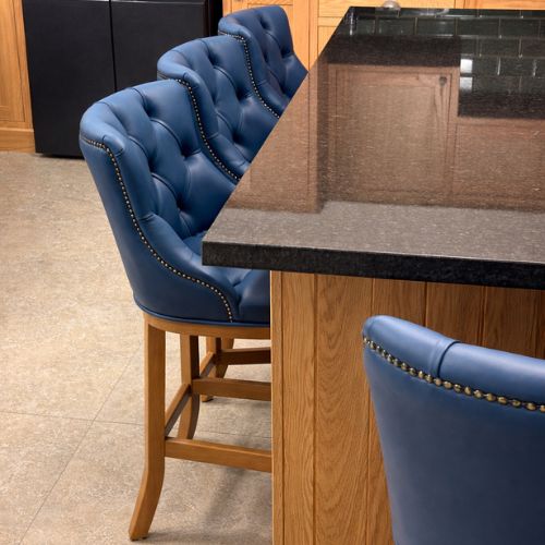 Luxury blue tufted leather bar stools at modern kitchen island with granite countertop