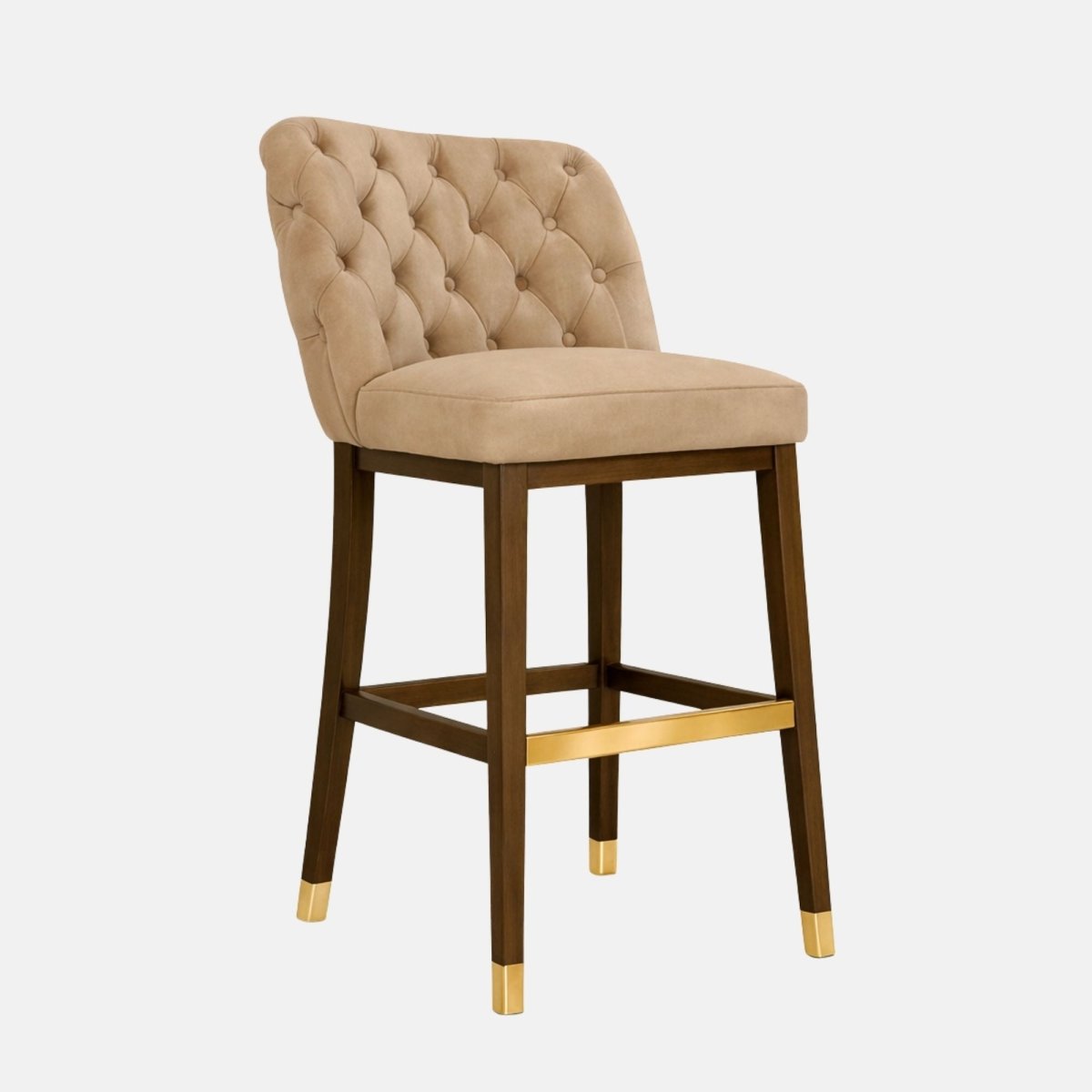 Front three-quarter view of a beige, button-tufted upholstered bar stool with a thick seat cushion, dark wooden legs, and brass footrest and leg caps, photographed on a white background.