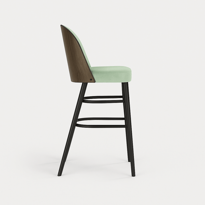 A barstool with pastel green velvet upholstery, black legs, and a dark wood veneer backrest, shown in a straight side profile view against a plain light background with a subtle shadow.