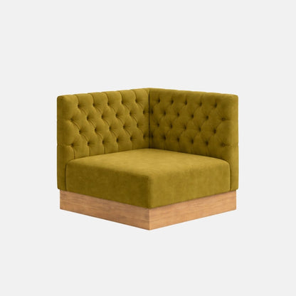 Corner banquette seating in green upholstered fabric with button tufting and a wooden base, designed for booth-style seating on a neutral background.