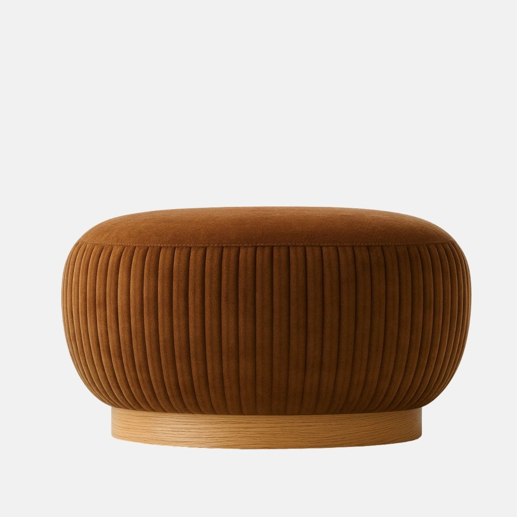 Rust velvet round ottoman with vertical pleated sides and natural oak base modern upholstered footstool or coffee table for living room or hotel lounge.