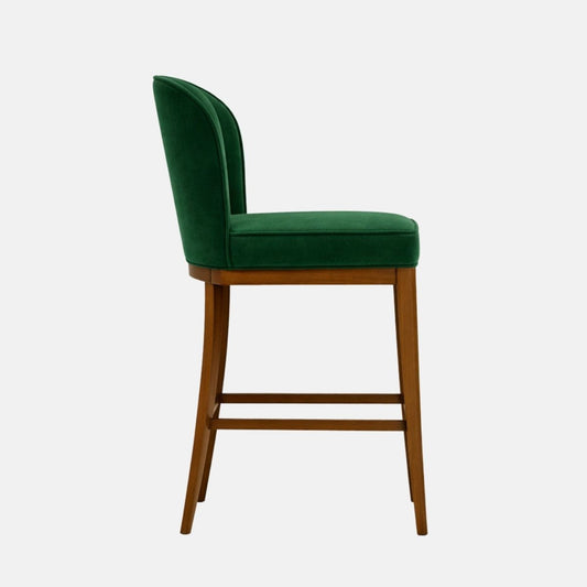 Green velvet bar-height stool with tall curved back and wooden legs, on white background.