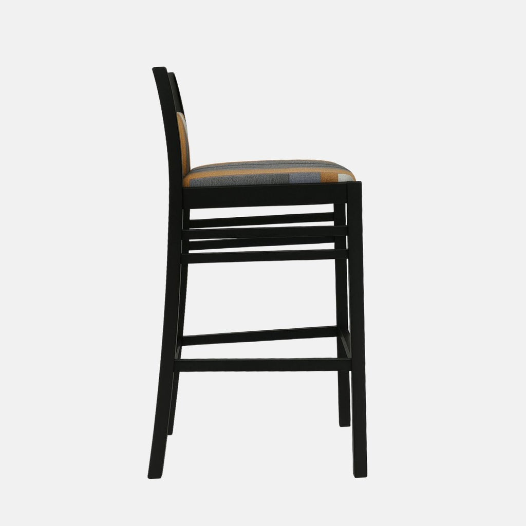 Modern bar stool with a black wooden frame, square backrest, and multicolored geometric upholstered seat and back panel in shades of grey, orange, and beige.