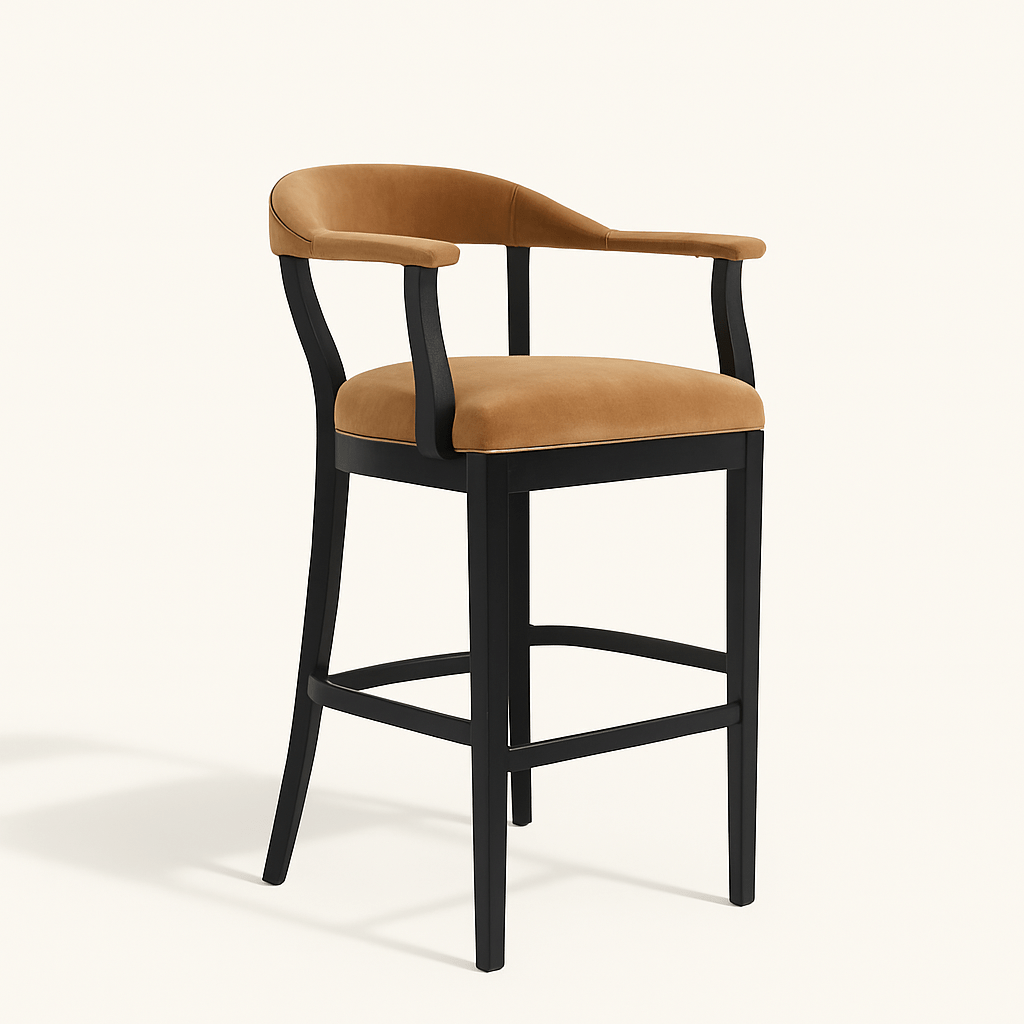 A modern bar stool with a matte black wooden frame and caramel beige velvet upholstery. The chair features curved back legs, a low curved backrest, and padded armrests, all upholstered in matching velvet. The side profile highlights the sleek, ergonomic design and horizontal footrest. The stool is set against a plain off-white background.