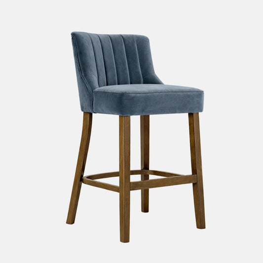 Blue velvet upholstered bar stool with channel back design and wooden legs, front angle view.