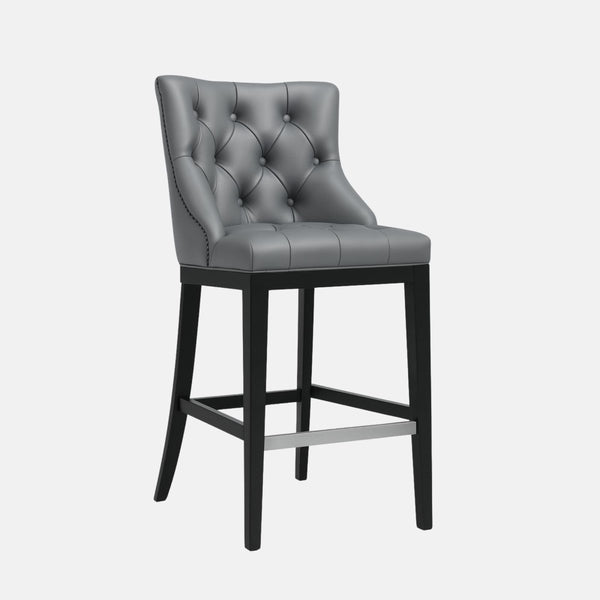 Elegant bar stool with tufted grey leather upholstered backrest and seat, black wooden legs, and metal footrest.