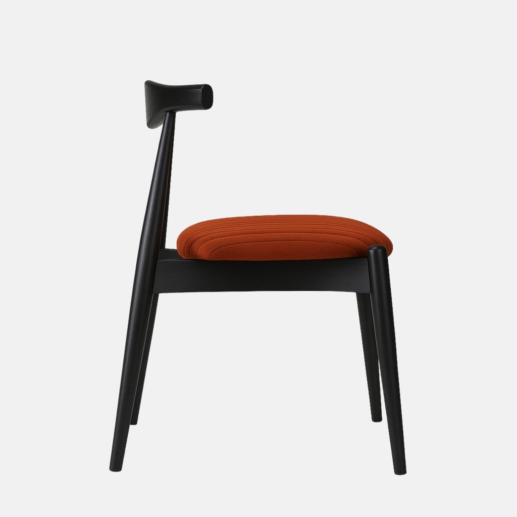 Modern dining chair with a black wooden frame and sculpted backrest, featuring a round burnt orange upholstered seat with vertical stitching, set against a light grey background