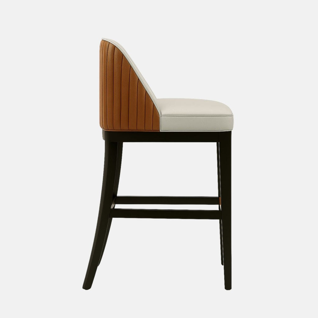 Modern bar stool with a curved, upholstered backrest in light beige leather and vertical stitching. The outer back is covered in tan fabric, and the seat is cushioned in matching beige. It features a dark wooden frame with a footrest accent in a warm wood tone.