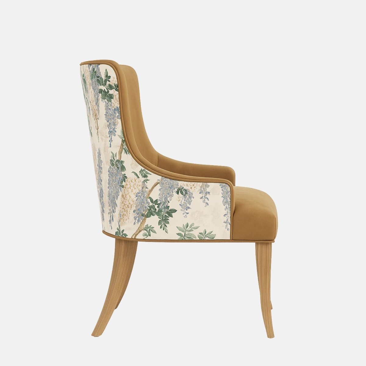 Upholstered dining chair in warm tan fabric with gently curved arms and cushioned seat, featuring a floral-patterned fabric panel on the outer back and natural wooden legs, shown on a white background