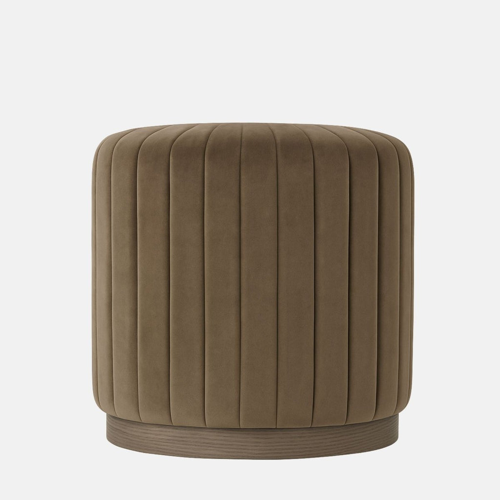 Taupe velvet round ottoman with vertical channel upholstery and natural wood base modern upholstered stool or side table for living room, bedroom, or hotel lounge.