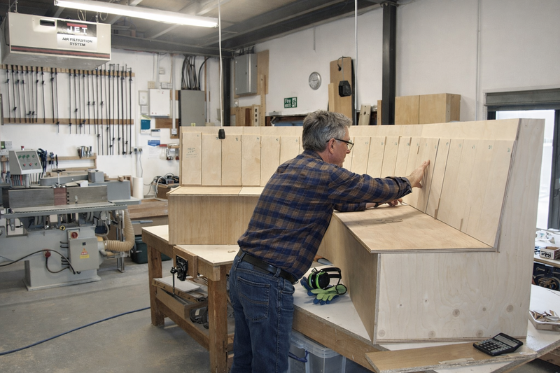 Furniture maker assembling a wooden frame structure in a woodworking workshop