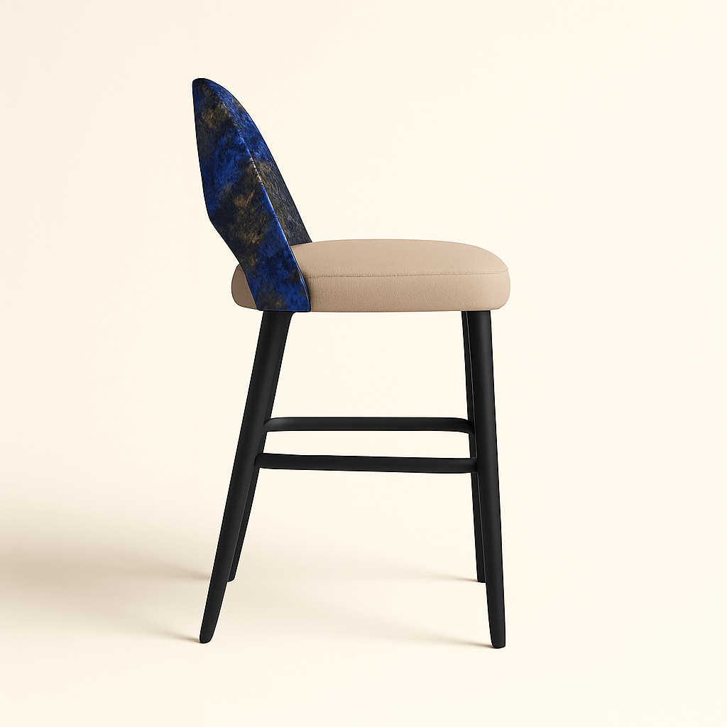A modern barstool with a beige cushioned seat, matte black wooden legs, and a curved backrest upholstered in a textured abstract fabric featuring deep blue, black, and gold tones, shown from a side view against a soft beige background.