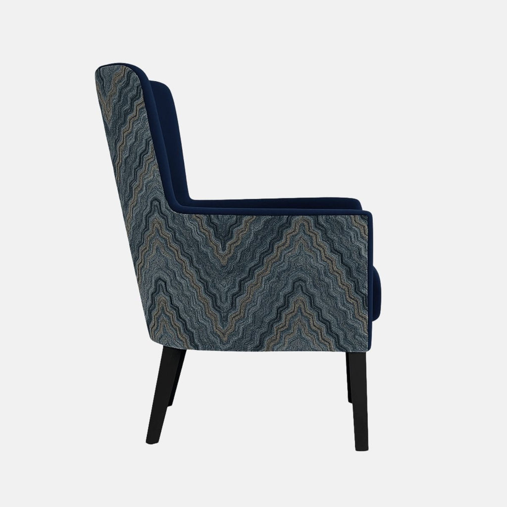 Modern wingback armchair with deep navy blue upholstery, patterned blue fabric on the outer sides, cushioned seat, and black wooden legs.