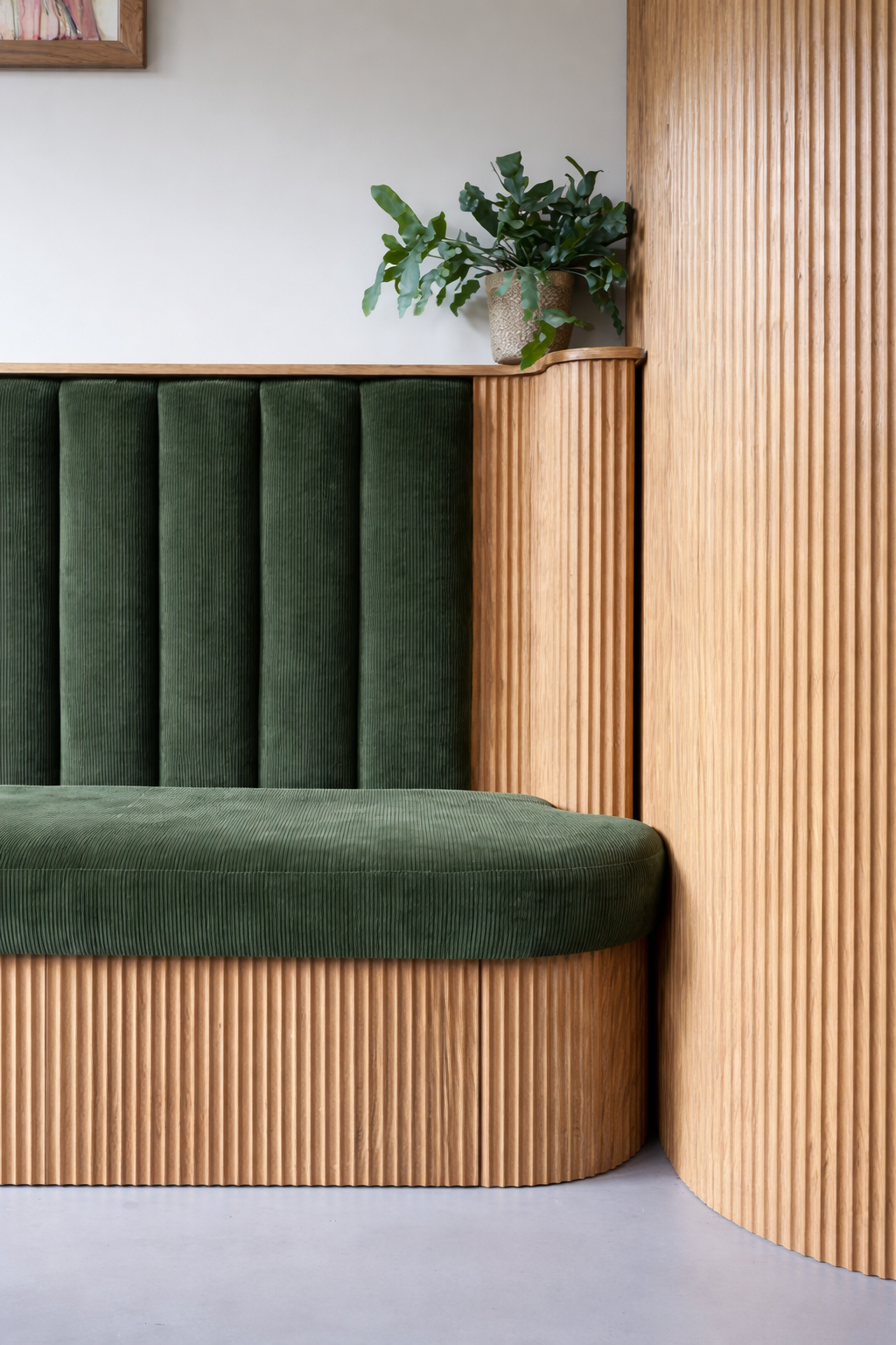 Modern green velvet banquette seating with fluted wood paneling and built-in bench design