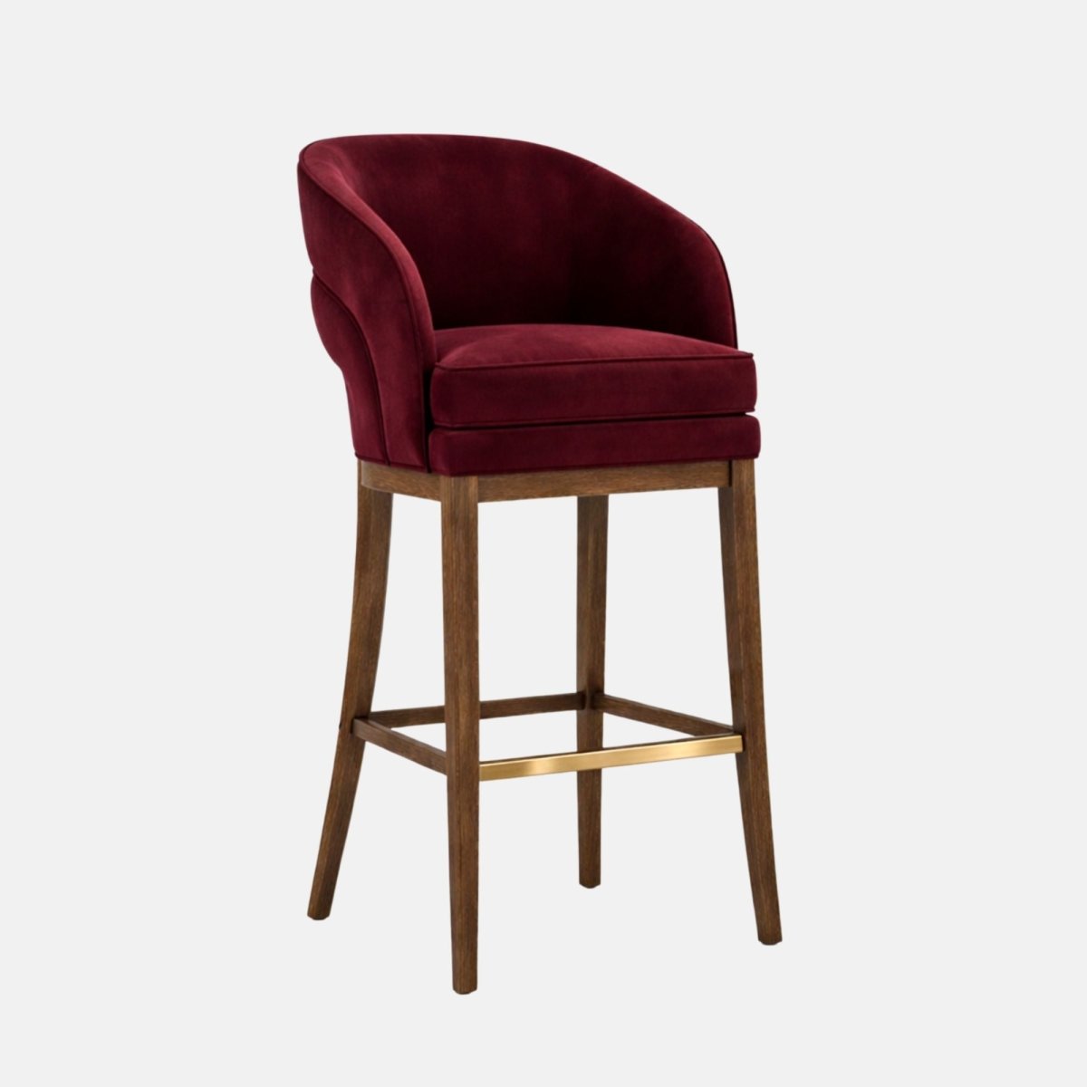 A burgundy velvet bar stool with a curved wraparound tub back and thick cushioned seat, on dark wooden legs with square stretchers and a brass footrest, photographed on a white background.
