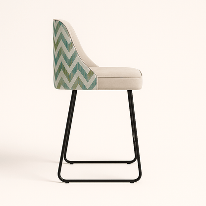 Modern bar and kitchen counter stool with a cream upholstered seat and vertical channel tufting, featuring a chevron-patterned fabric on the back and a sleek black metal sled base, set against a neutral background.