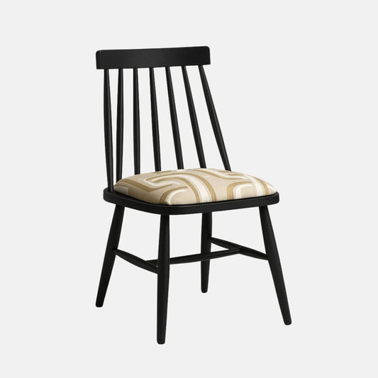 A modern Windsor-style dining chair with a matte black wooden frame and a cushioned seat upholstered in a beige geometric-patterned fabric, shown in a clean studio setting with soft shadows and a neutral light background.
