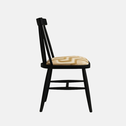 A modern Windsor-style dining chair with a matte black wooden frame and a cushioned seat upholstered in a beige geometric-patterned fabric, shown in a clean studio setting with soft shadows and a neutral light background.
