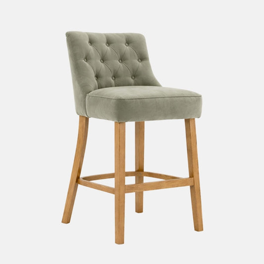 Green upholstered bar stool with button tufted back, cushioned seat and wooden legs, front angle view
