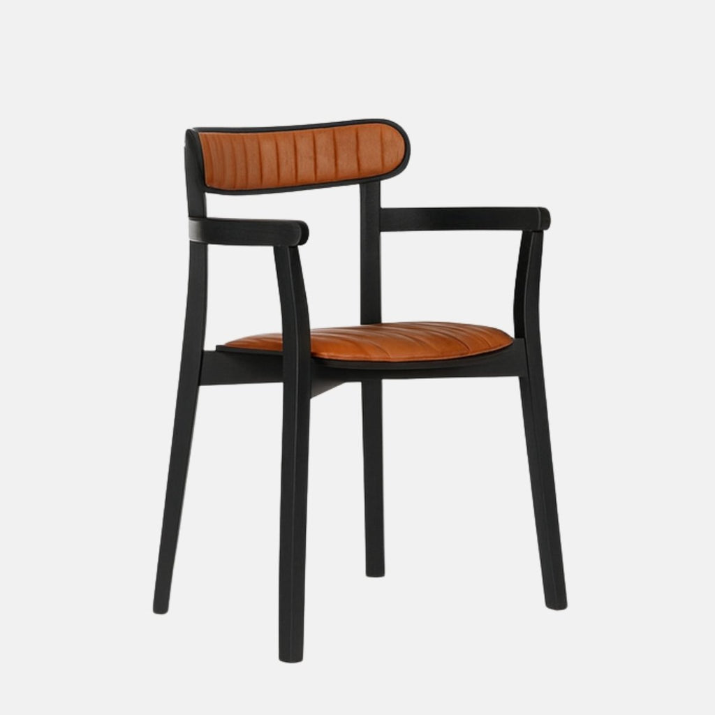 Modern armchair with a slim black wooden frame and armrests, featuring caramel brown leather upholstery on the seat and rounded backrest with vertical stitching, set against a light grey background