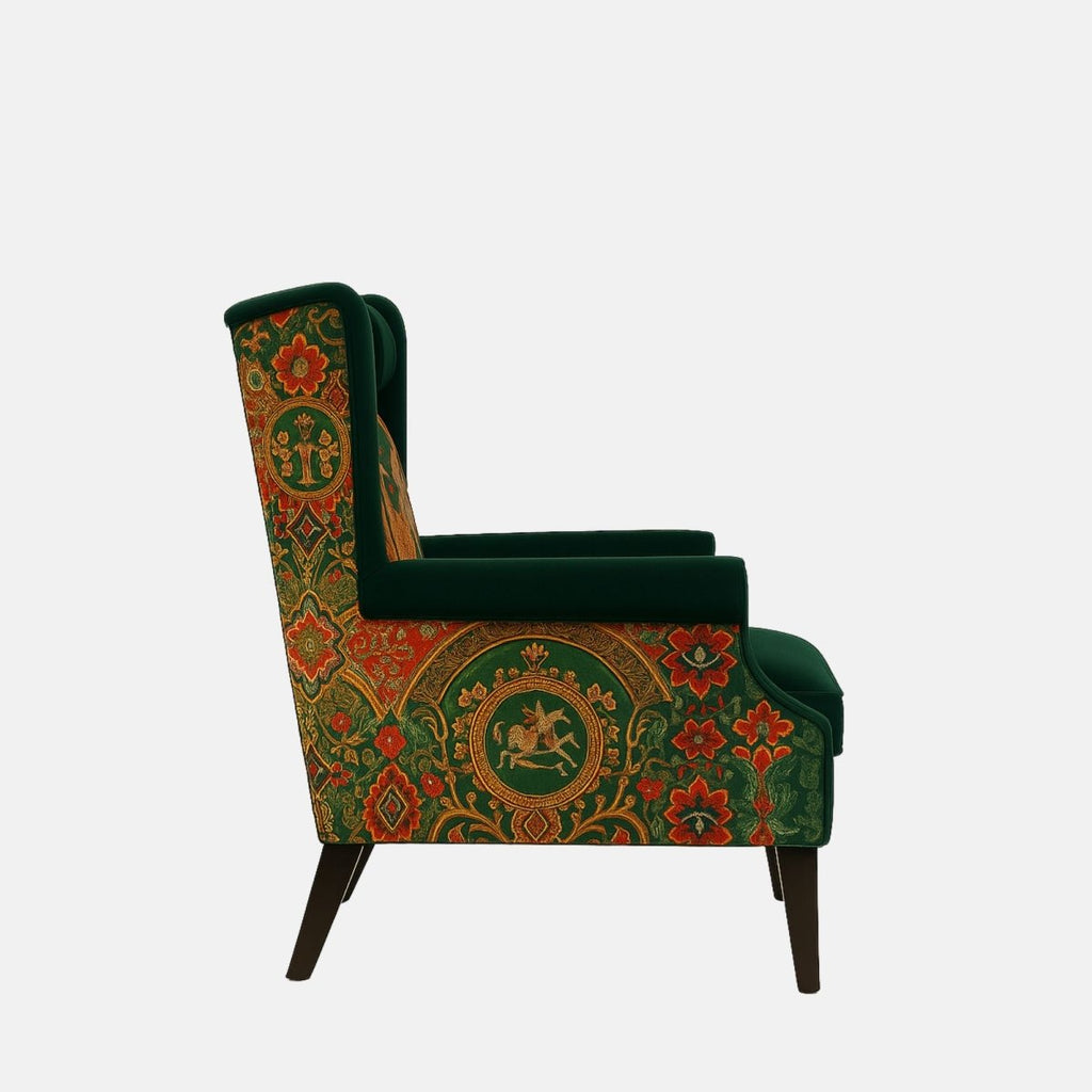 Dark green wingback armchair with a cushioned seat and headrest, featuring vibrant patterned upholstery on the back and sides with a central embroidered scene depicting a figure and a winged horse