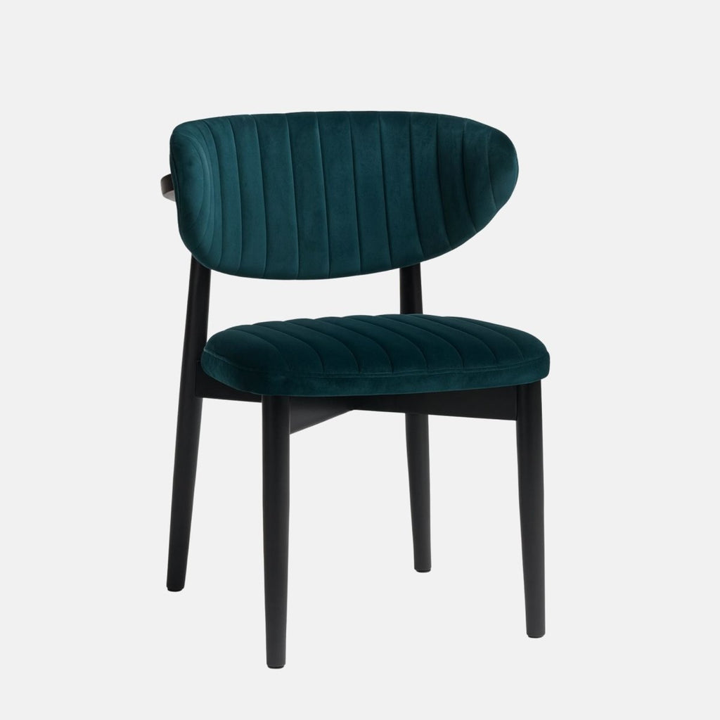 Modern dining chair with a black wooden frame and legs, featuring deep teal velvet upholstery on the curved backrest and seat with vertical channel stitching, set against a light grey background
