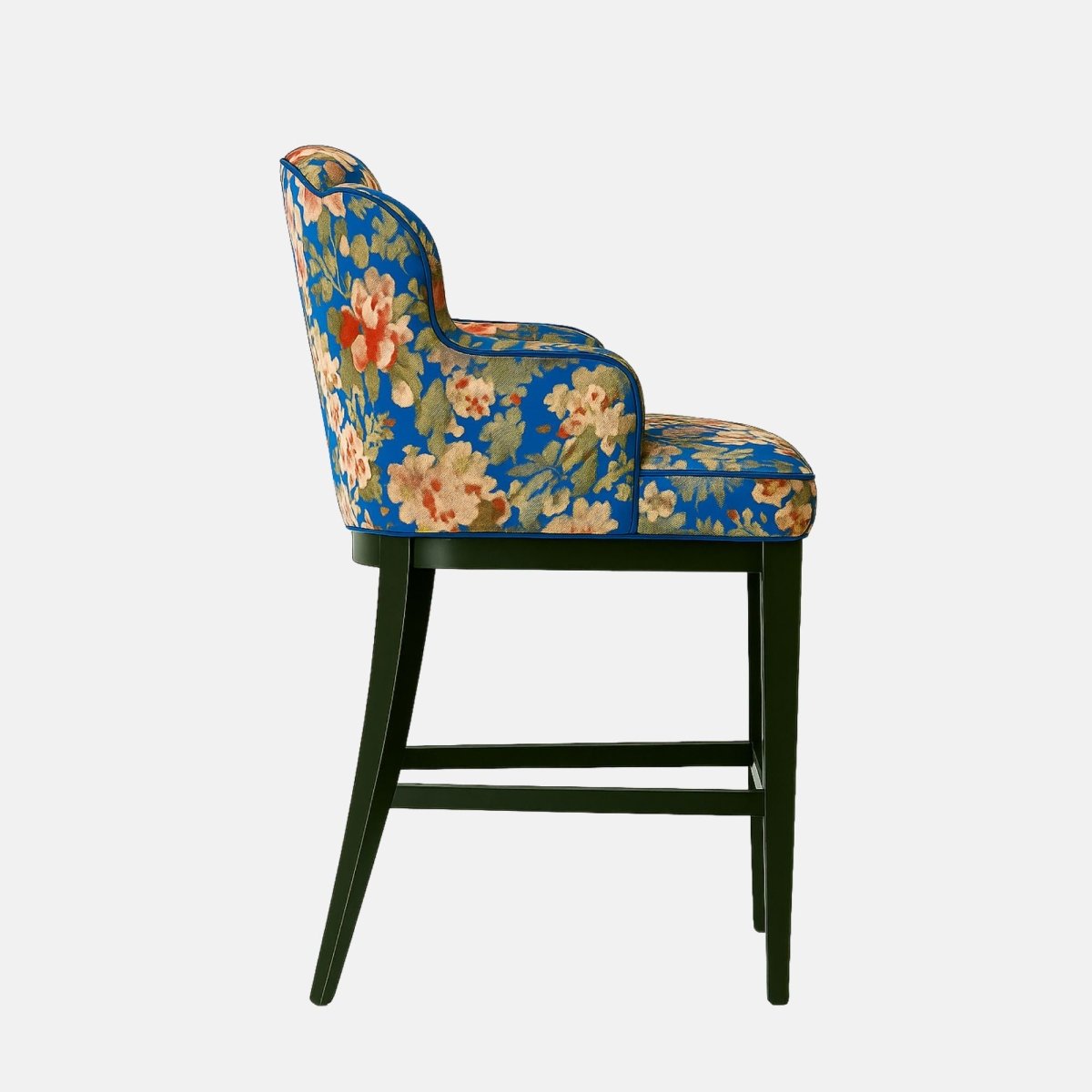 Elegant bar stool with a scalloped backrest and arm design, upholstered in a vibrant blue floral fabric featuring red, cream, and green tones. The seat is plush and supported by a sleek black wooden frame, blending vintage charm with modern sophistication.
