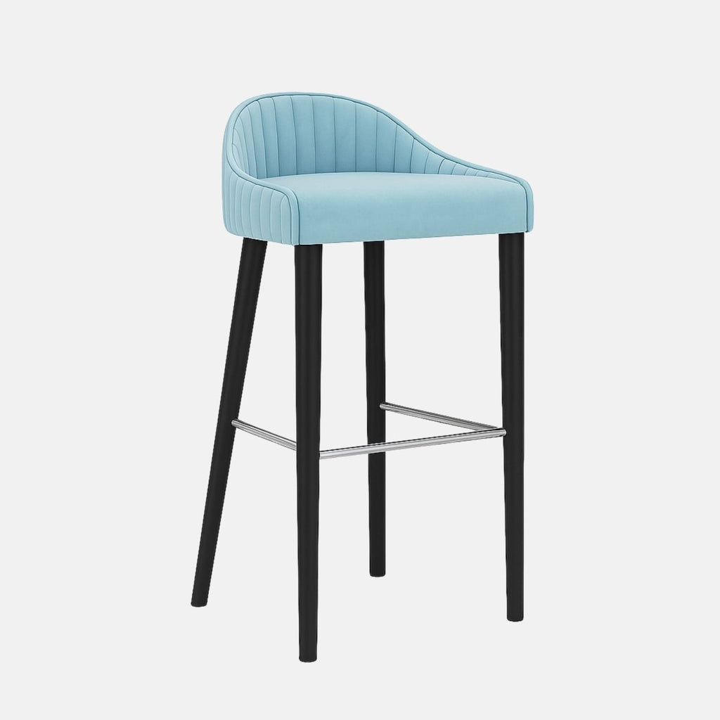 Contemporary bar stool with light blue upholstered seat and back featuring vertical channel stitching, black tapered legs, and a metal footrest.