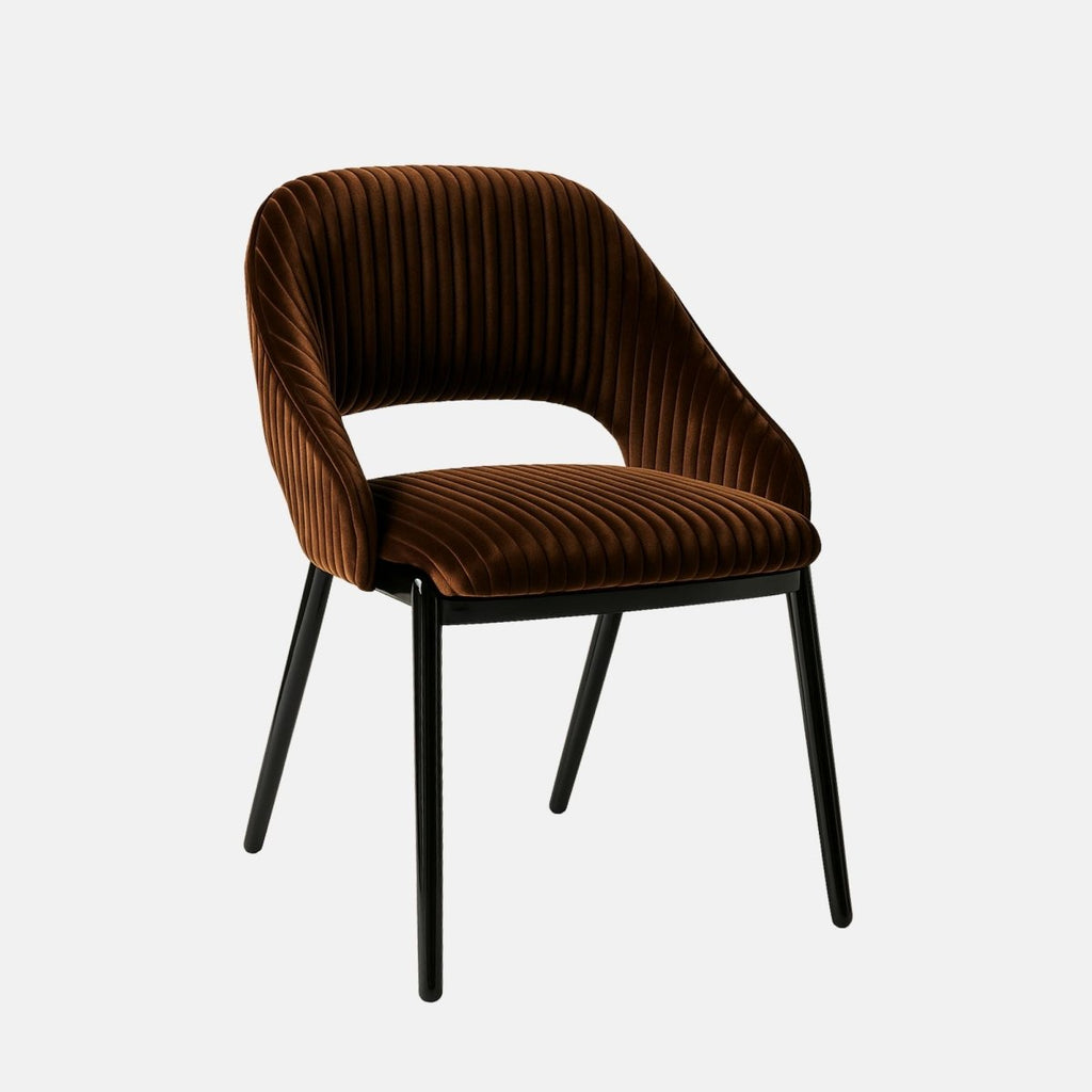 Contemporary dining chair with black metal legs and a curved backrest, upholstered in rich brown velvet with vertical channel stitching and an open lower back design, set against a light grey background