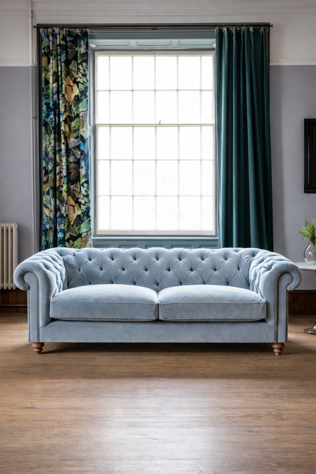 Light blue velvet Chesterfield sofa with deep button tufting in an elegant living room