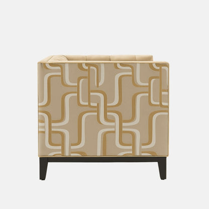 A contemporary beige armchair with tufted upholstery, geometric patterned side panels in cream and tan, and black wooden legs.