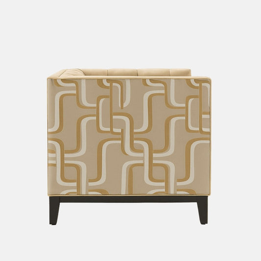 A contemporary beige armchair with tufted upholstery, geometric patterned side panels in cream and tan, and black wooden legs.