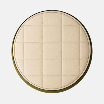Two-tone round ottoman with olive green fabric body and cream quilted seat on black base modern upholstered stool for living room, bedroom, or hotel lounge.