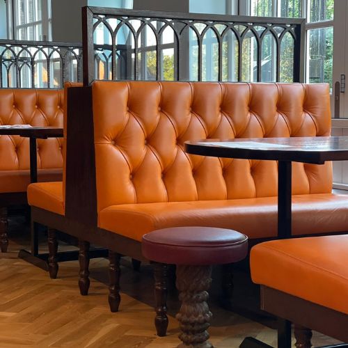 Luxury restaurant interior with tufted orange leather booth seating and wooden tables