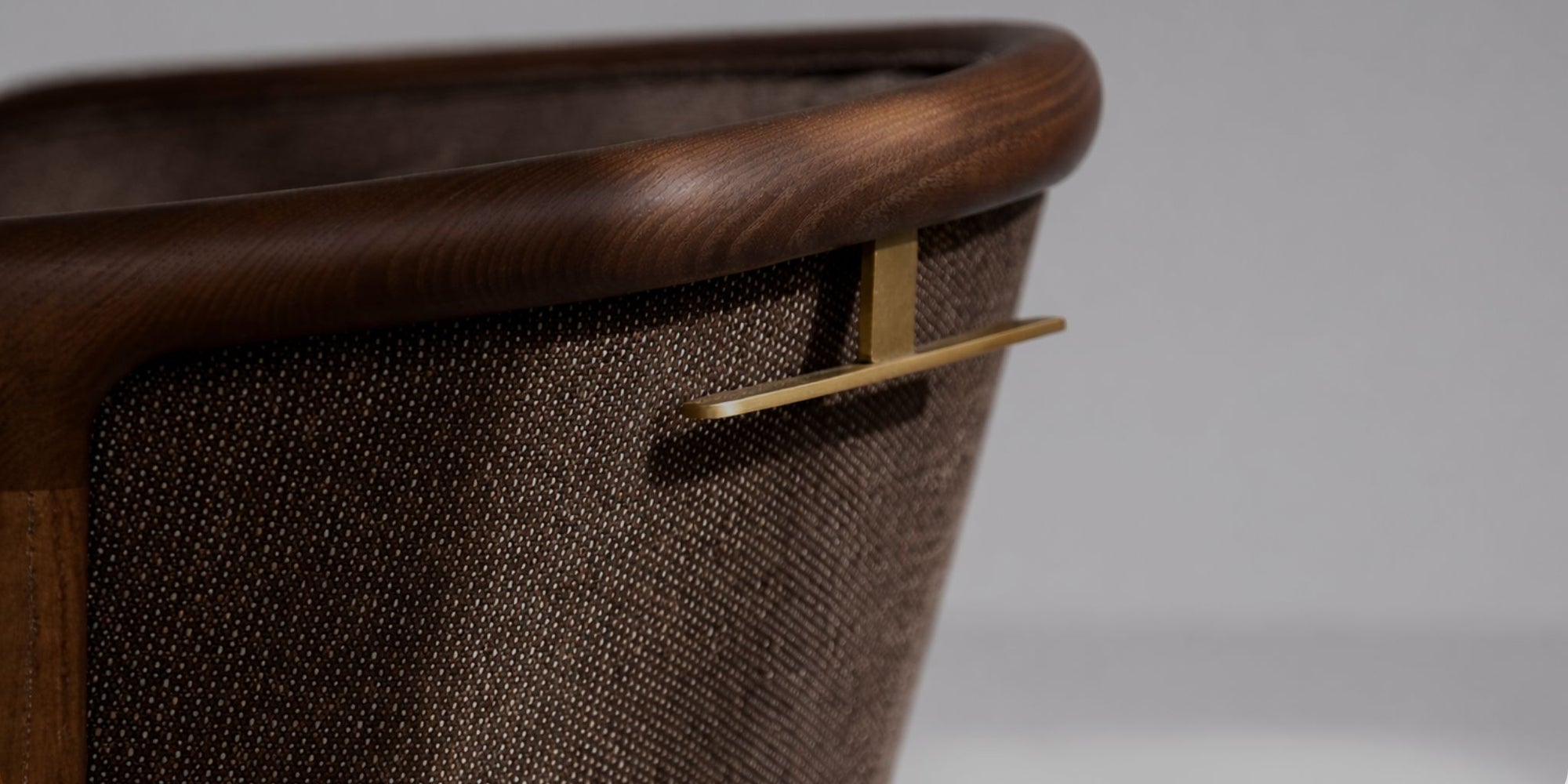 Close-up detail of upholstered furniture with curved wood frame and brass handle
