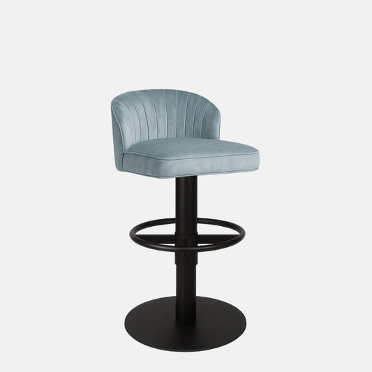 Light blue upholstered bar stool with curved backrest, vertical stitching, and black pedestal base with circular footrest.