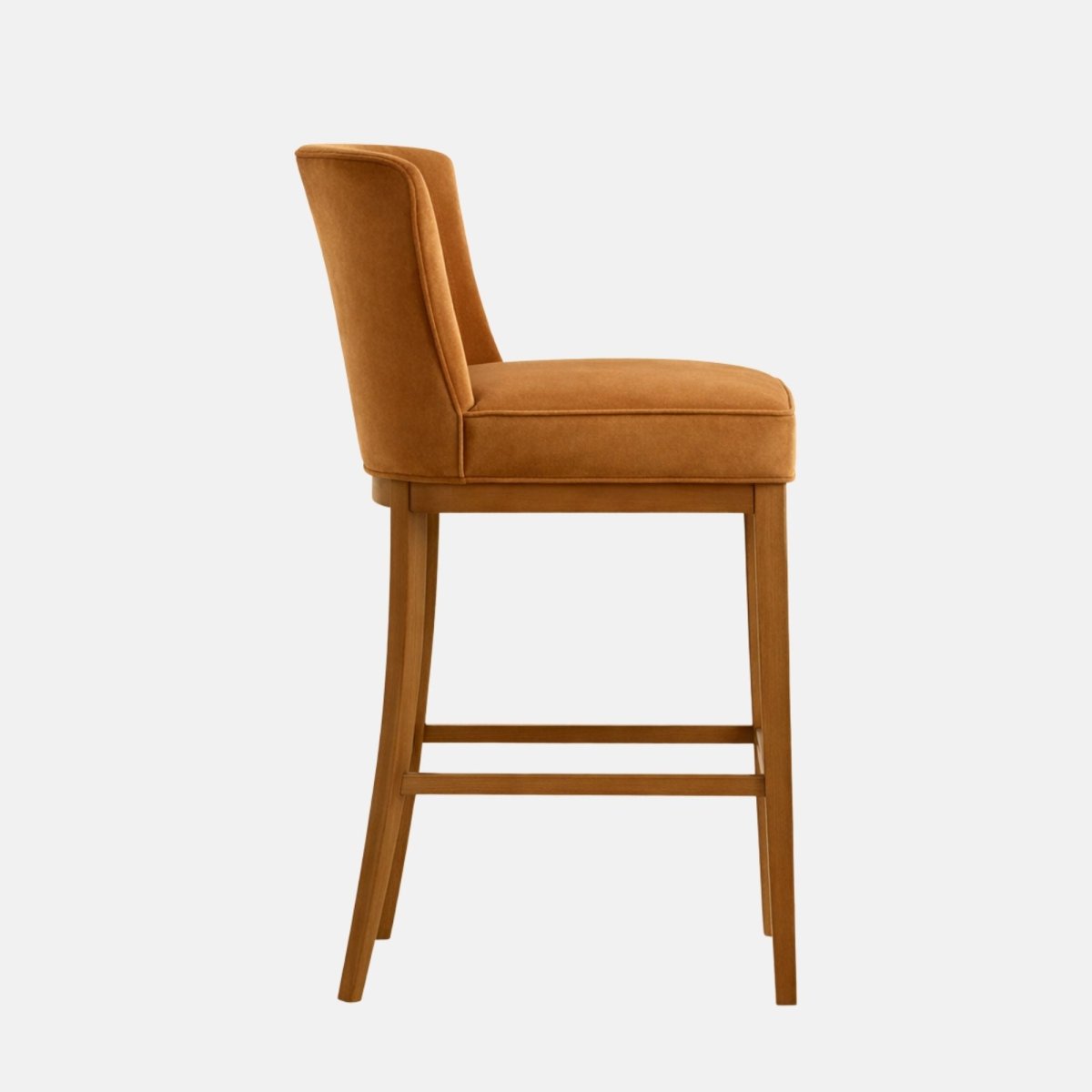 Caramel/tan upholstered bar-height stool shown in side profile, with a simple curved backrest and thick padded seat on a warm oak wooden frame with four legs and straight stretcher bars, photographed on a white background.