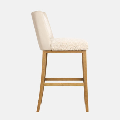 Side view of a cream sherpa upholstered bar stool with a smooth upholstered back panel, cushioned seat, and light wood legs with lower stretcher rails.
