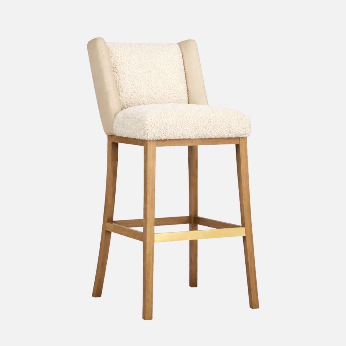 Cream sherpa upholstered bar stool with padded side panels on the backrest, cushioned seat, and light wood legs with a brass footrest bar.