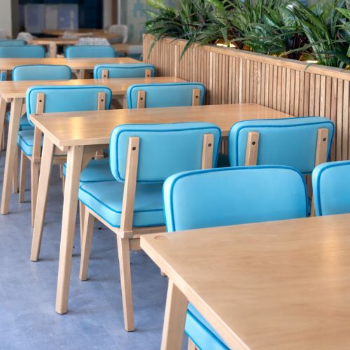 Modern cafe seating area with blue upholstered chairs and wooden tables