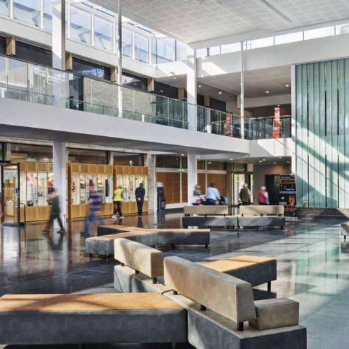 Modern corporate lobby interior with open space seating, glass railings and natural light