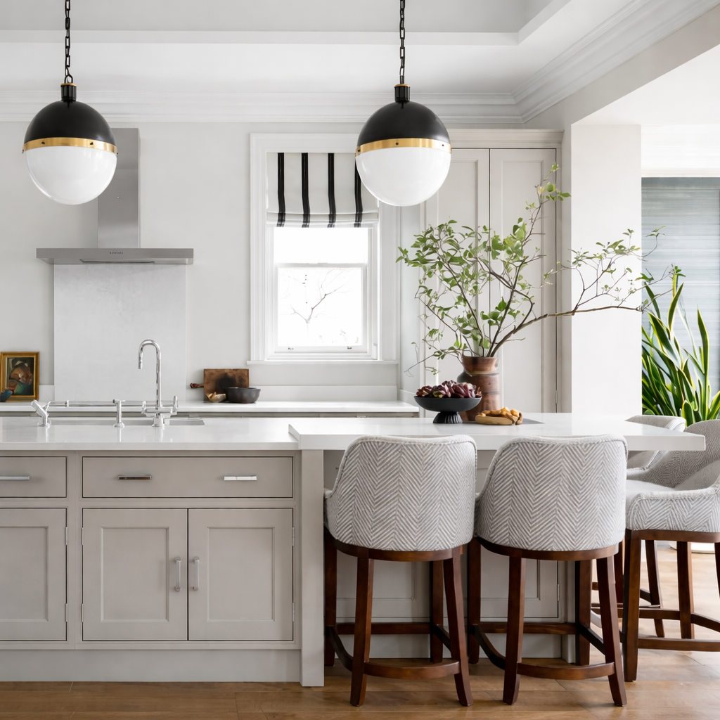 Elegant modern kitchen with breakfast bar seating, upholstered counter stools, and black pendant lights.