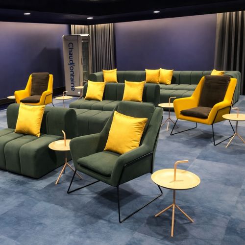 Modern lounge seating area with green sofa, yellow armchairs and contemporary furniture