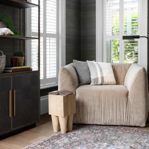 Cozy modern reading nook with upholstered armchair, side table and natural window light