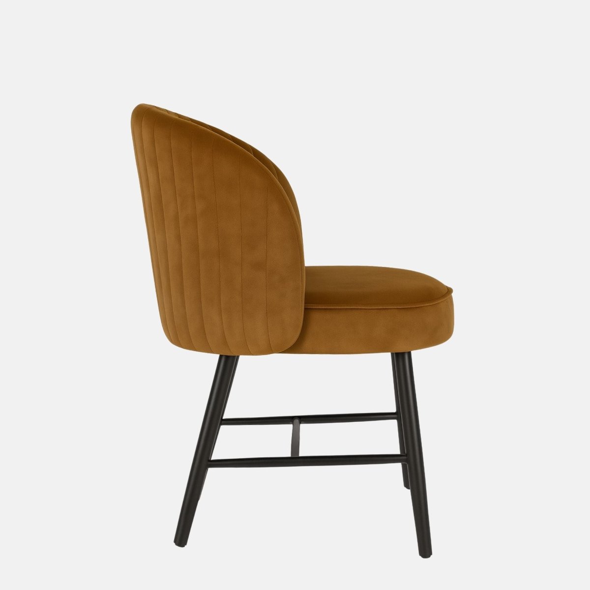 Modern dining chair with black metal legs and a rounded backrest, upholstered in warm caramel velvet with vertical channel stitching, set against a light grey background
