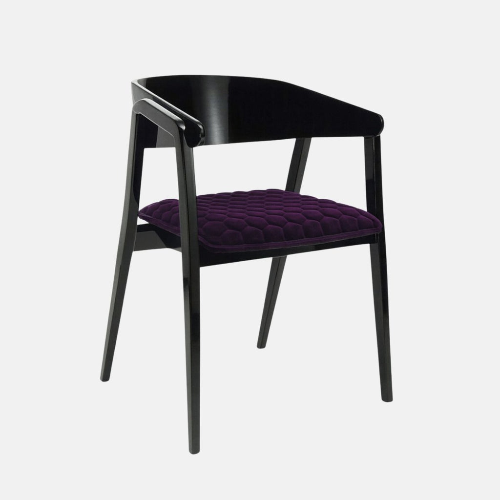 Stylish modern chair with a glossy black wooden frame and open curved backrest, featuring a deep purple velvet seat cushion with a geometric quilted pattern, set against a light grey background.