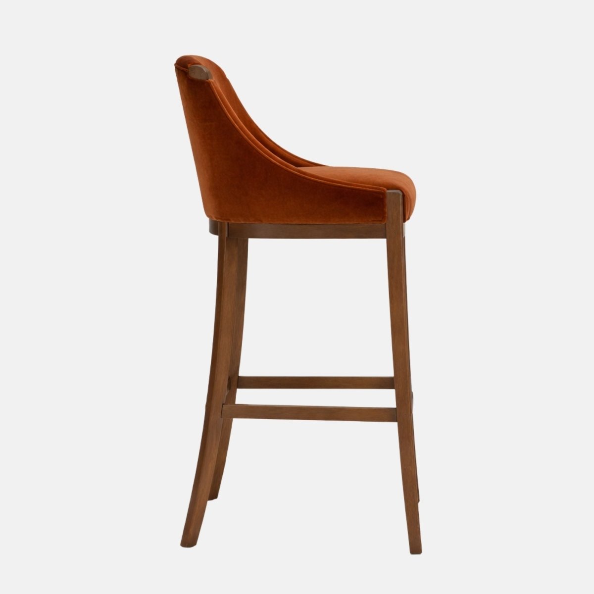 Side view of a rust brown velvet bar stool with a curved wraparound back, padded seat, and dark wooden legs with lower stretcher rails.