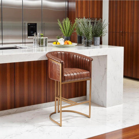 alt="Luxury bar stool with sawing detail in brown leather and sleek gold metal frame"