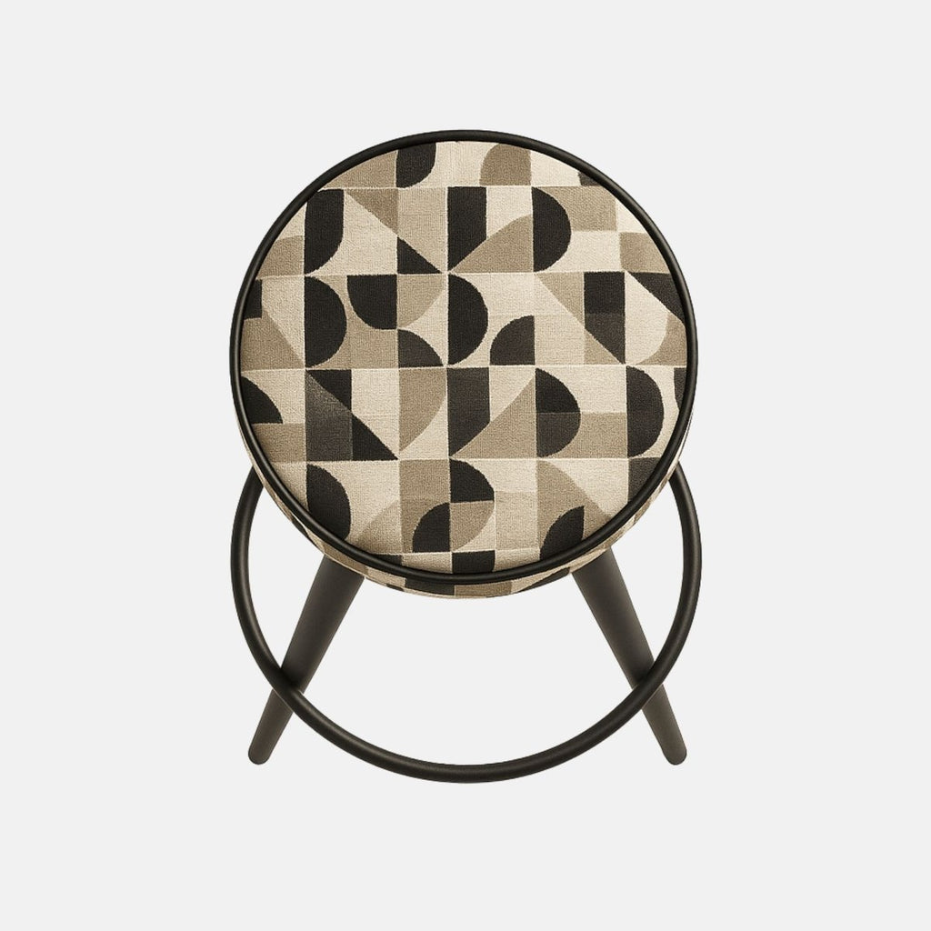 Modern bar stool with a round cushioned seat in a geometric beige and black fabric, supported by black tapered legs connected with a circular footrest.
