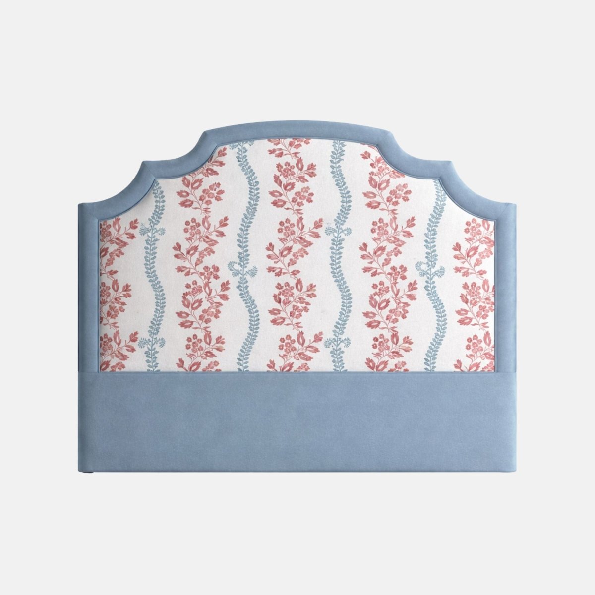 Upholstered headboard with a scalloped blue frame and floral patterned fabric in soft red and blue tones, set against a plain background.